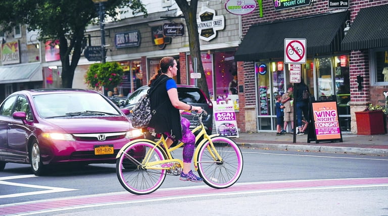 A woman bikes through downtown Patchogue