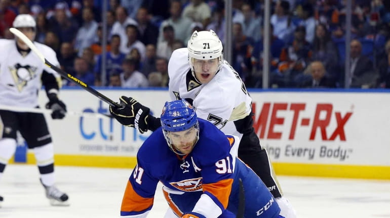 John Tavares of the Islanders is tripped up by Evgeni...