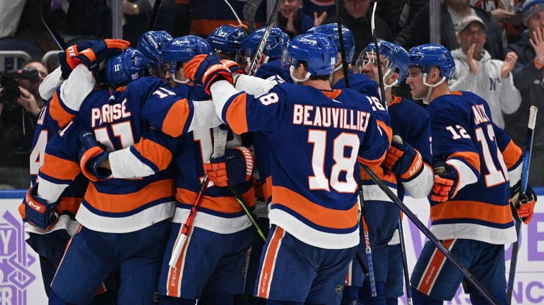 Islanders players celebrate an overtime goal by Zach Parise for...