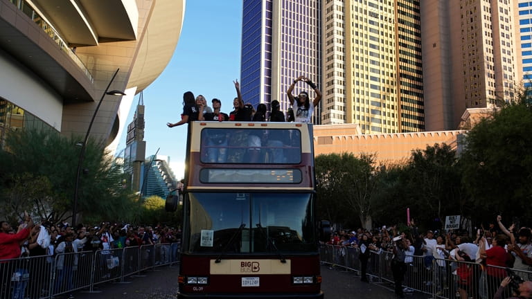 Las Vegas Aces players celebrate while riding a bus during...