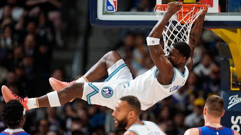 Minnesota Timberwolves guard Anthony Edwards hangs from the rim after...