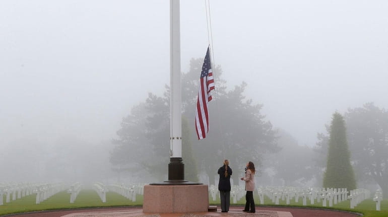 U.S. staff members raise the U.S. flag at the Colleville...