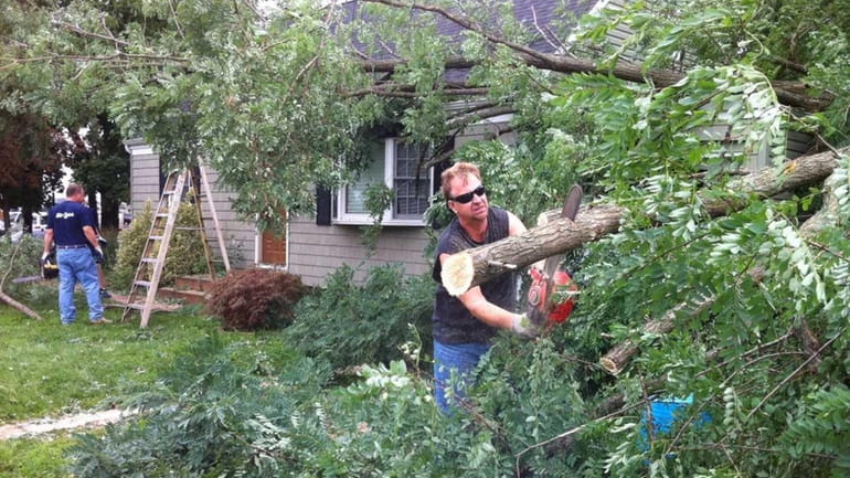 John Marter, 45, uses a chain saw to cut up...