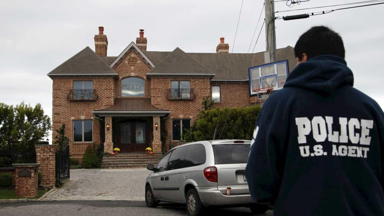 A law enforcement agent stands outside the home of Mark...