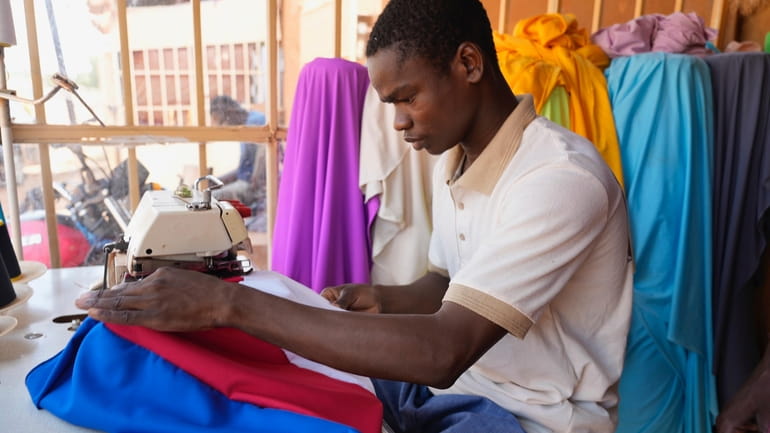 A seamster makes a Russian flag in Niamey, Niger, Thursday,...