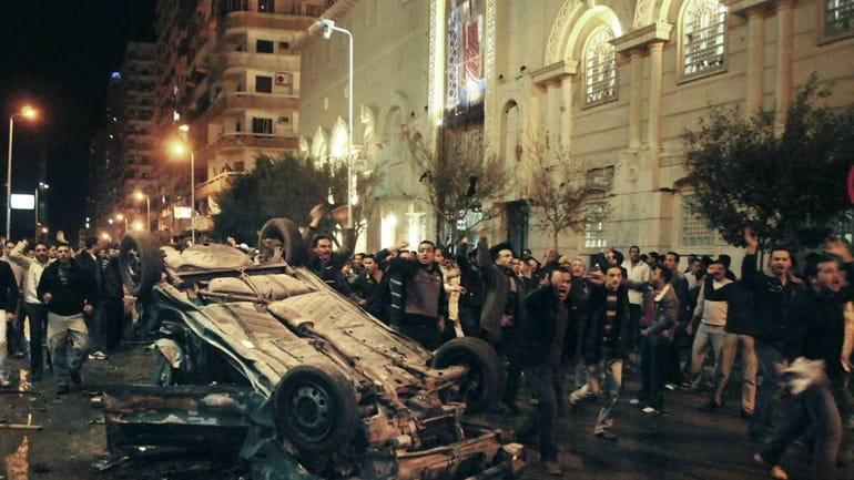 An exploded car is seen in front of a Coptic...