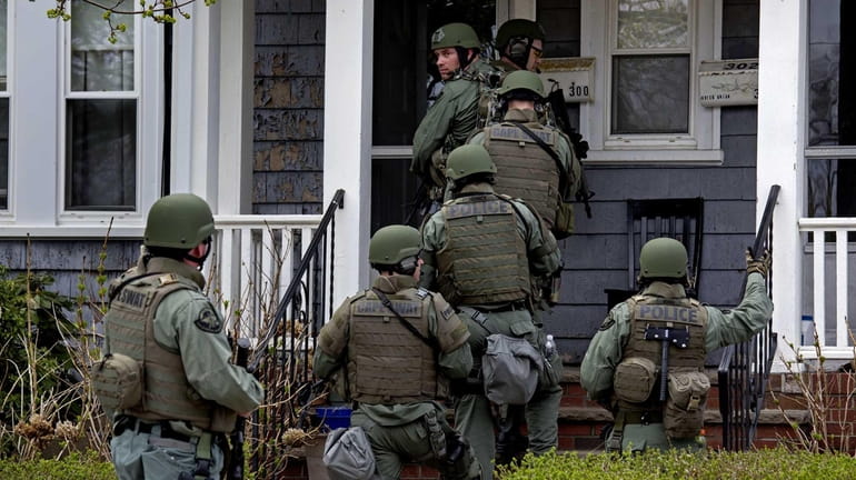 Heavily armed police officers perform a house-to-house search in Watertown,...