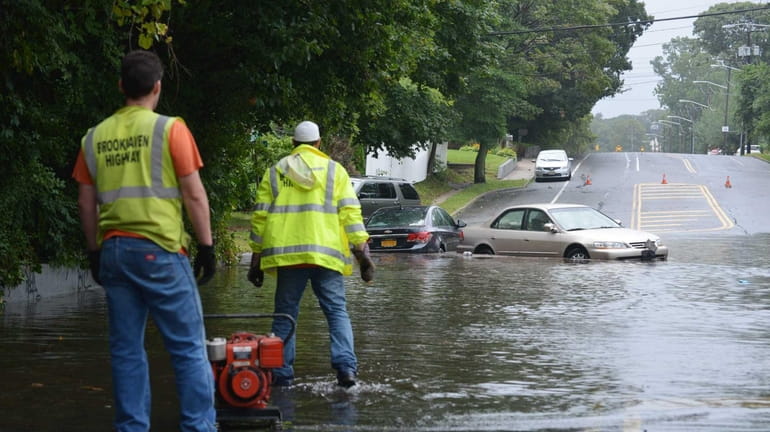 Brookhaven Highway Department workers pump water on Boyle Street in...