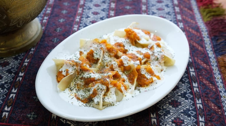 Mantu dumplings are double-drizzled with sauces of tomato and yogurt at...
