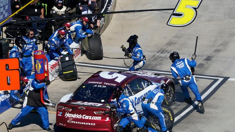 Crew members perform a pit stop on driver Kyle Larson's...