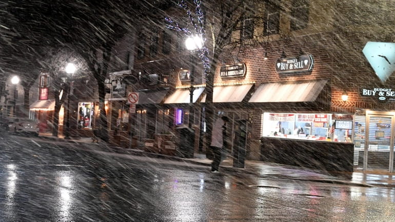 People make their way on a snowy Main Street in...