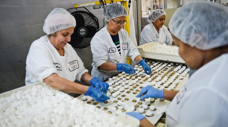 Employees process caramel chocolate candy inside the Nassau Candy factory...