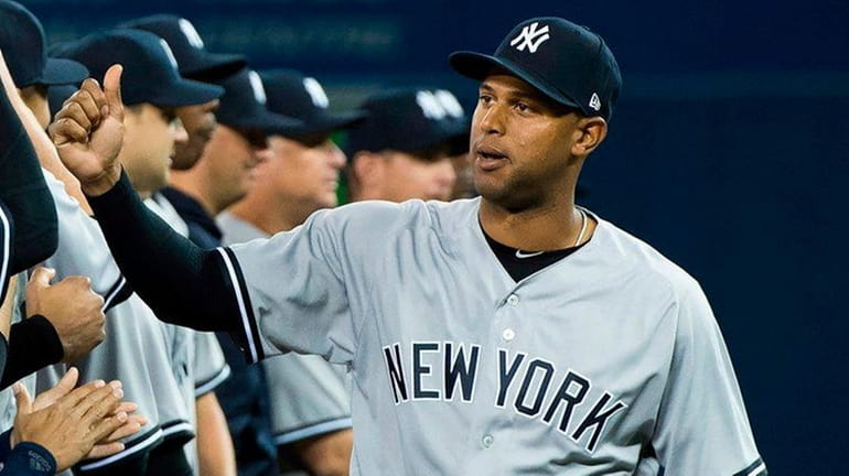 Yankees centerfielder Aaron Hicks, right, high-fives teammates as the Yankees...