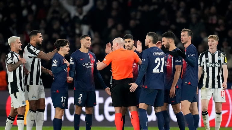 PSG players surround Referee Szymon Marciniak appealing for a penalty...