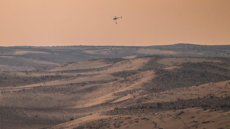 A helicopter returns from dumping water on hotspots from the...