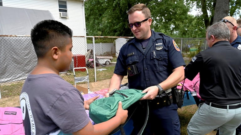 Nassau County Police Officer Dylan Hickman helps distribute backpacks Saturday in Westbury.