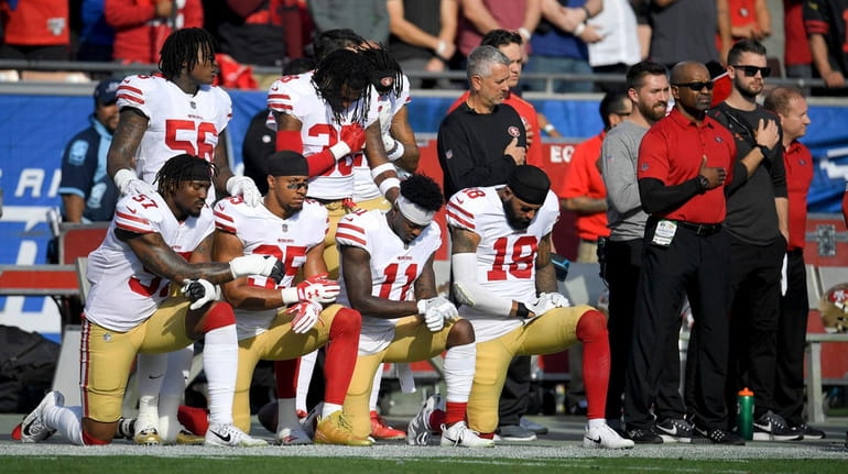 Members of the San Francisco 49ers kneel during the national...