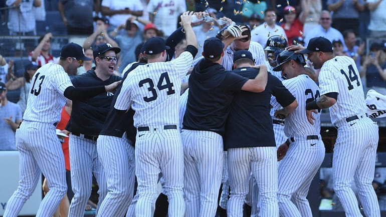 The Yankees' Aaron Judge is mobbed by teammates after his...