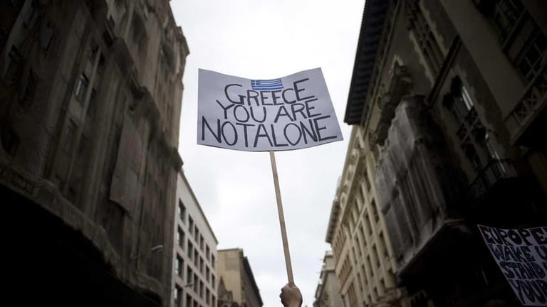 A demonstrator holds up a banner giving support to Greece...