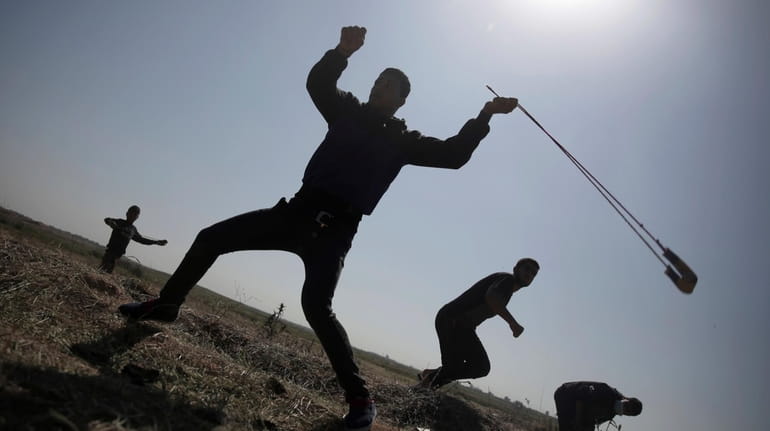 A Palestinian protester hurls stones at Israeli soldiers during a...