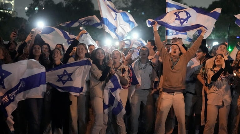 A group of Israelis celebrate as a helicopter carrying hostages...