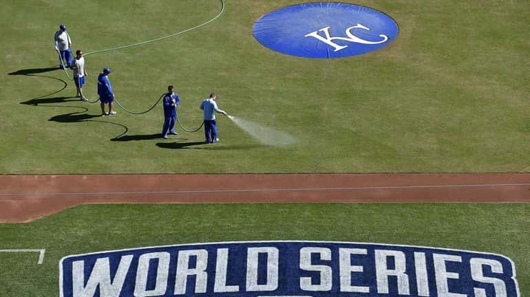 The Kansas City Royals grounds crew waters down the infield...