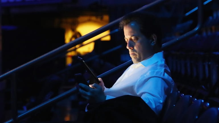 Broadcaster Kenny Albert checks his phone prior to the game...