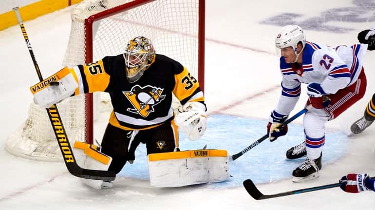 Penguins goaltender Tristan Jarry blocks a shot with the Rangers' Adam...
