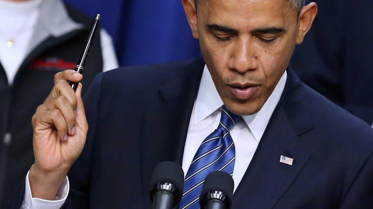 President Barack Obama holds a pen while saying he is...