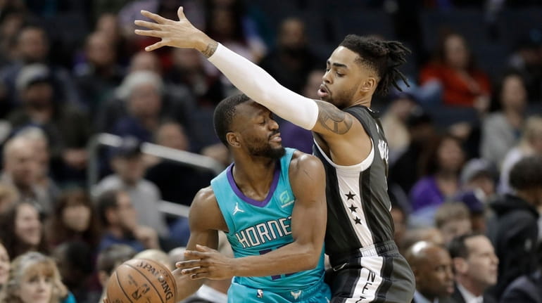 The Hornets' Kemba Walker, left, is fouled by the Nets'...