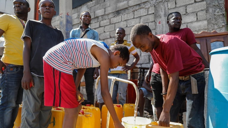 Residents fill their containers with potable water, in Port-au-Prince, Haiti,...