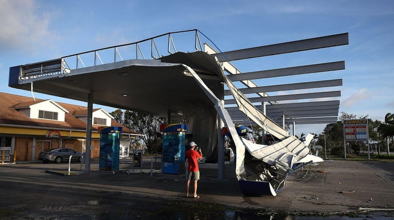 The roof of a gas station is shown damaged by...