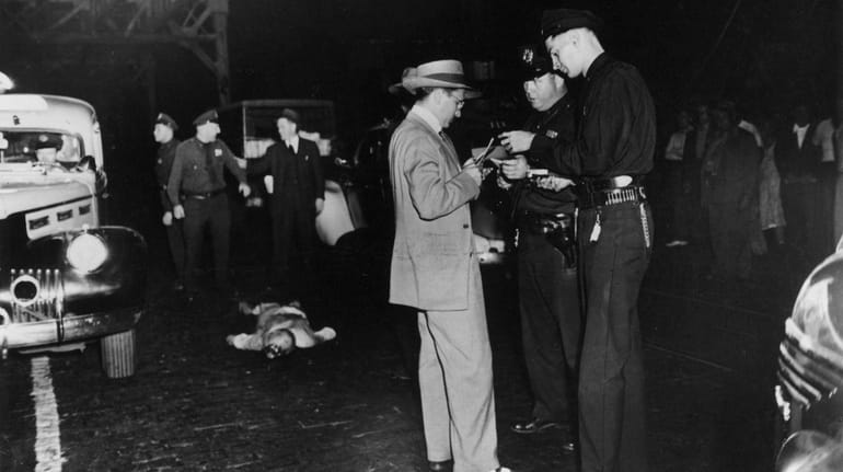 Weegee's photo of an accident victim surrounded by policemen under...