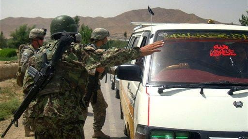 An Afghan soldier stops a mini bus as a U.S....