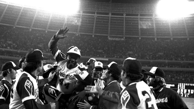 Teammates greet Hank Aaron at home plate after he hit his 715th career...
