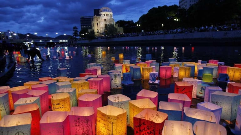Paper lanterns float along the Motoyasu River in front of...