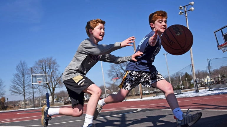 Eleven-year-old twins Liam, left, and Tommy McCarvill of Port Washington reach for...