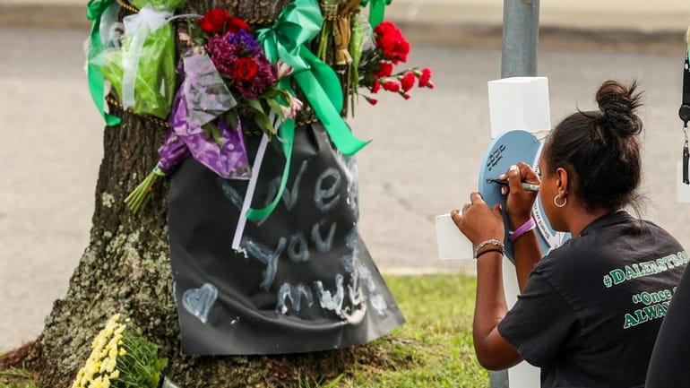 A student writes a message near a memorial outside of...