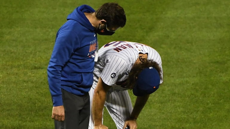Mets relief pitcher Robert Gsellman bends over in pain as...