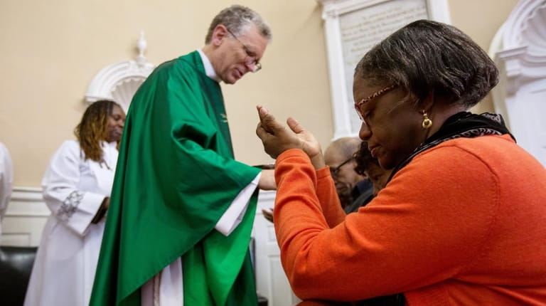 Interim minister Frederic A. Miller administers communion to parishioners during...