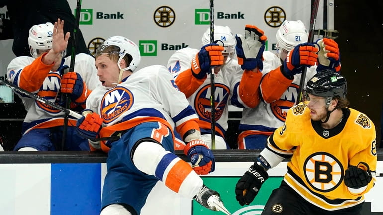 Islanders center Casey Cizikas, left, falls into the boards after...