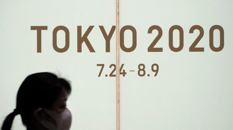 A woman walks past a large display promoting the Tokyo...