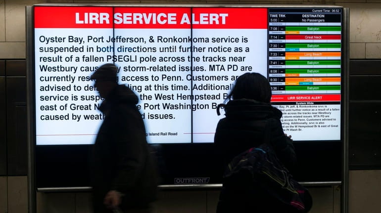 People walk past a sign advising LIRR passengers of a...