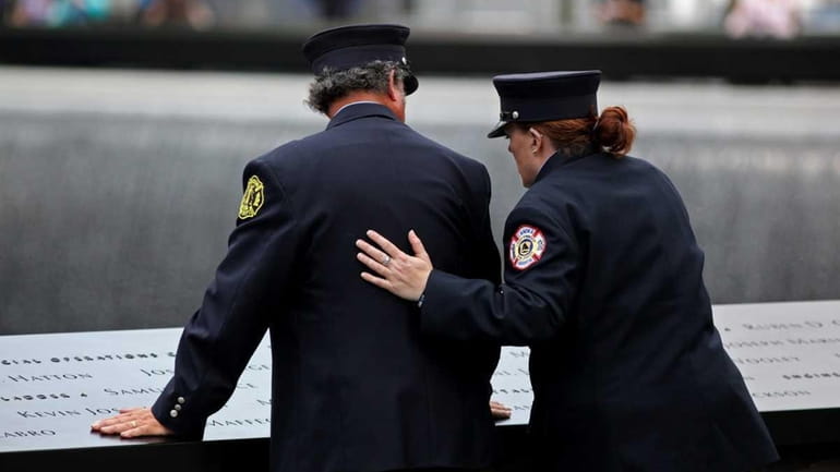 A first responder comforts another as they lean on the...