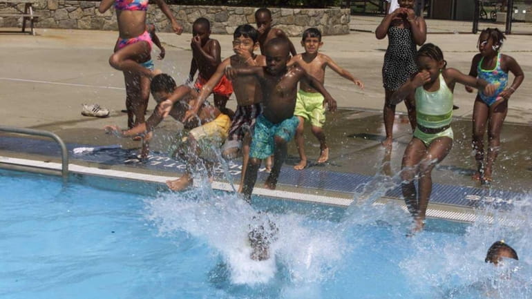 Kids jump in the water at the Geiger Lake Park...