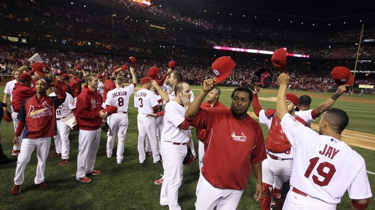 St. Louis Cardinals players wave their caps to acknowledge the...
