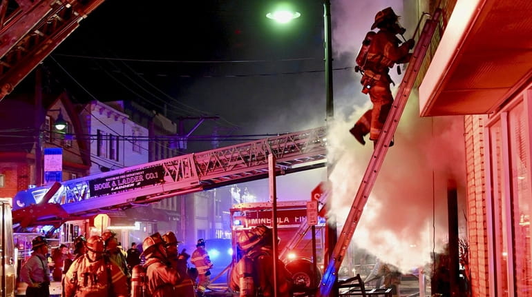 Firefighters battle a fire in a mixed-use building on Second Street near...