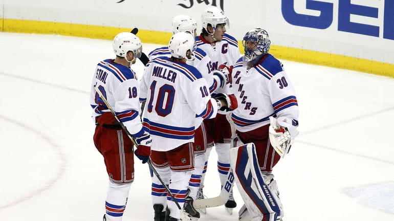 The New York Rangers celebrate with Henrik Lundqvist #30 after...