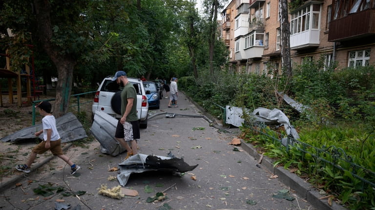 Local residents pass by debris that fell down from their...