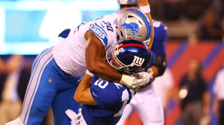 Eli Manning of the Giants is knocked down by Cornelius...